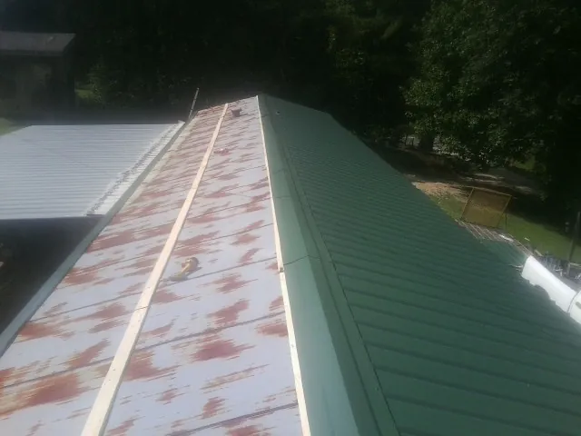 Old rusted panels beside newly installed green metal roofing — Wind Damage Roof Repair by Roofing Brothers in Norfolk